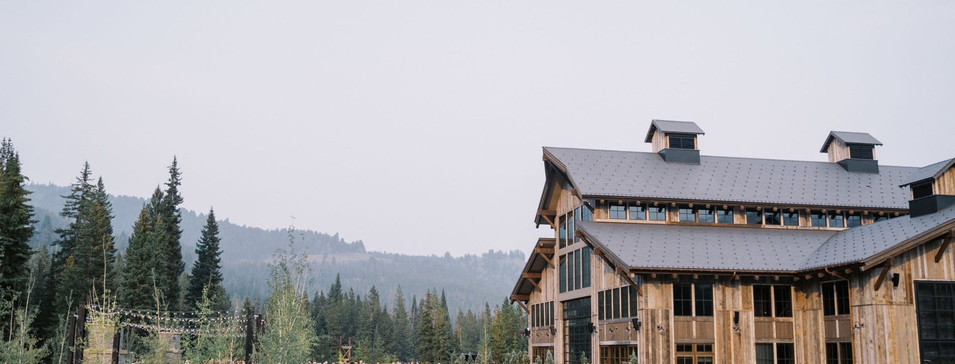 A large wooden house with a metal roof in the middle of a forest.