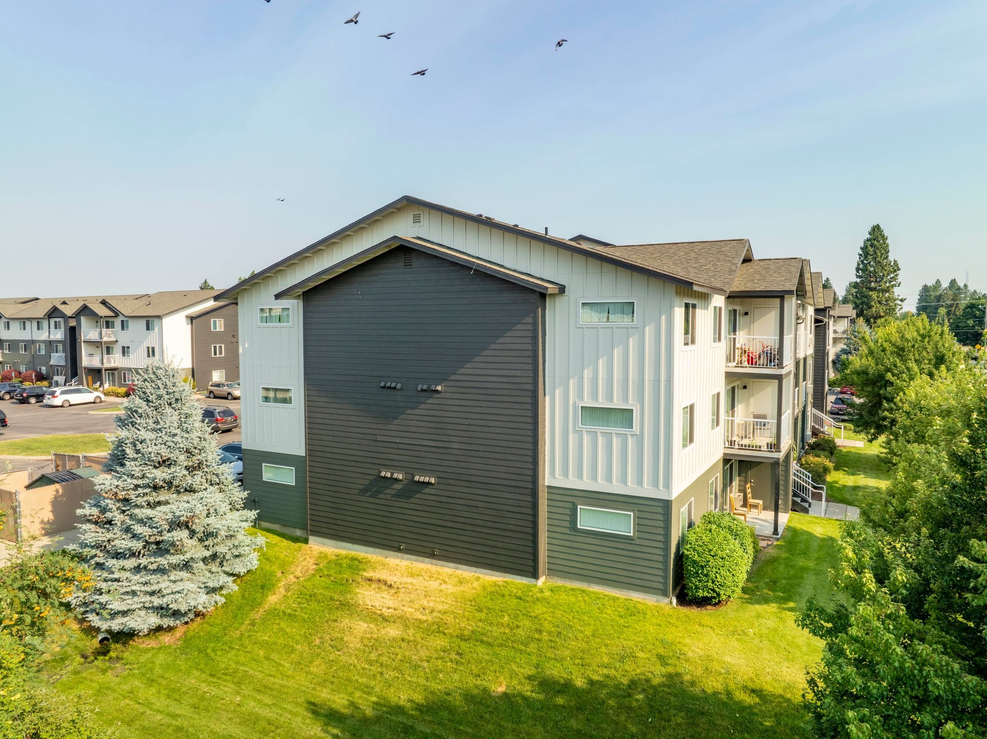 An aerial view of a large apartment building surrounded by trees and grass.