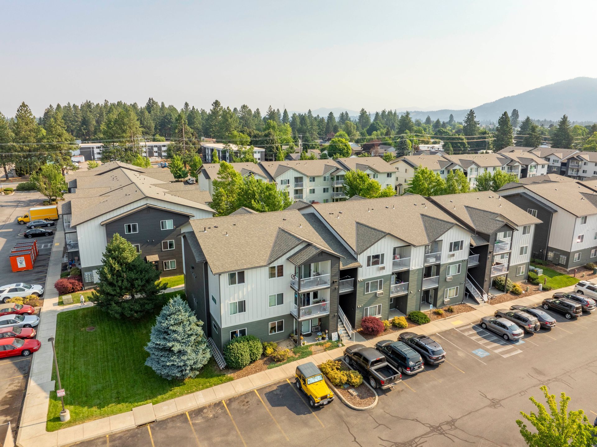 An aerial view of a apartment complex with cars parked in front of it.