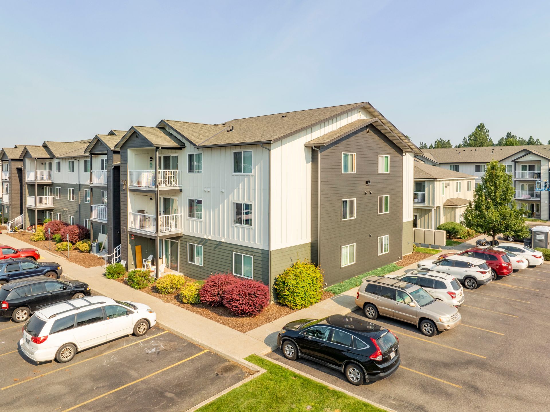 A large apartment building with a lot of cars parked in front of it.