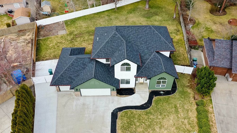 An aerial view of a large house with a black roof