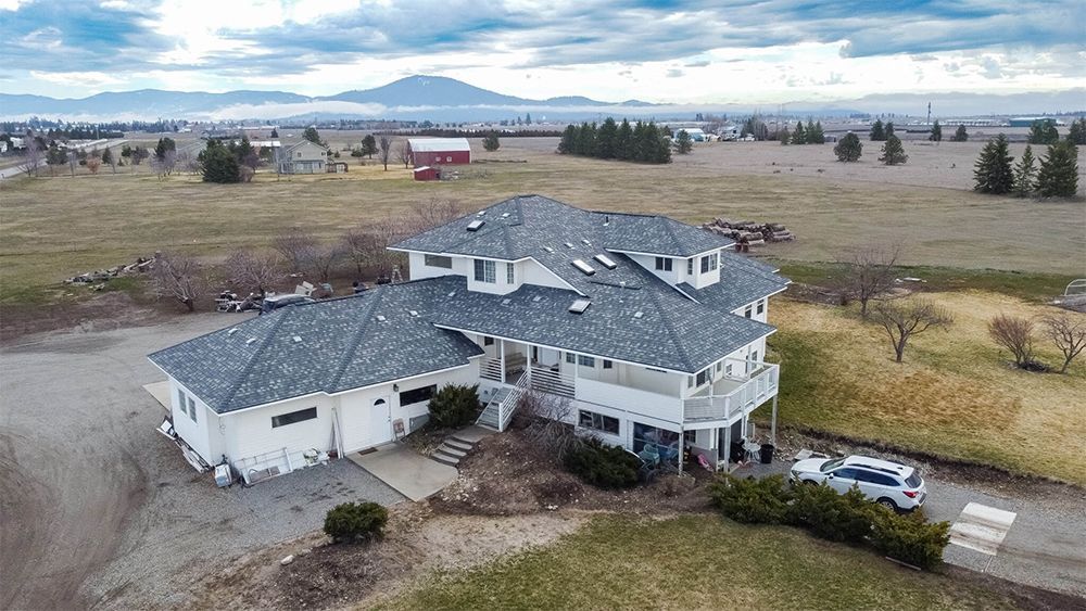 An aerial view of a large white house in the middle of a field
