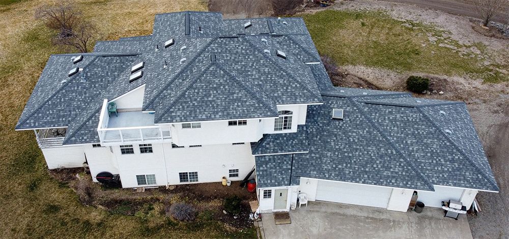 An aerial view of a large white house with a gray roof