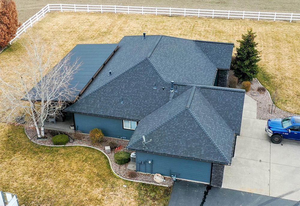 An aerial view of a blue house with a blue truck parked in front of it