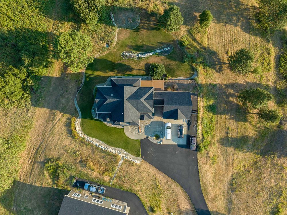 An aerial view of a house surrounded by trees and grass