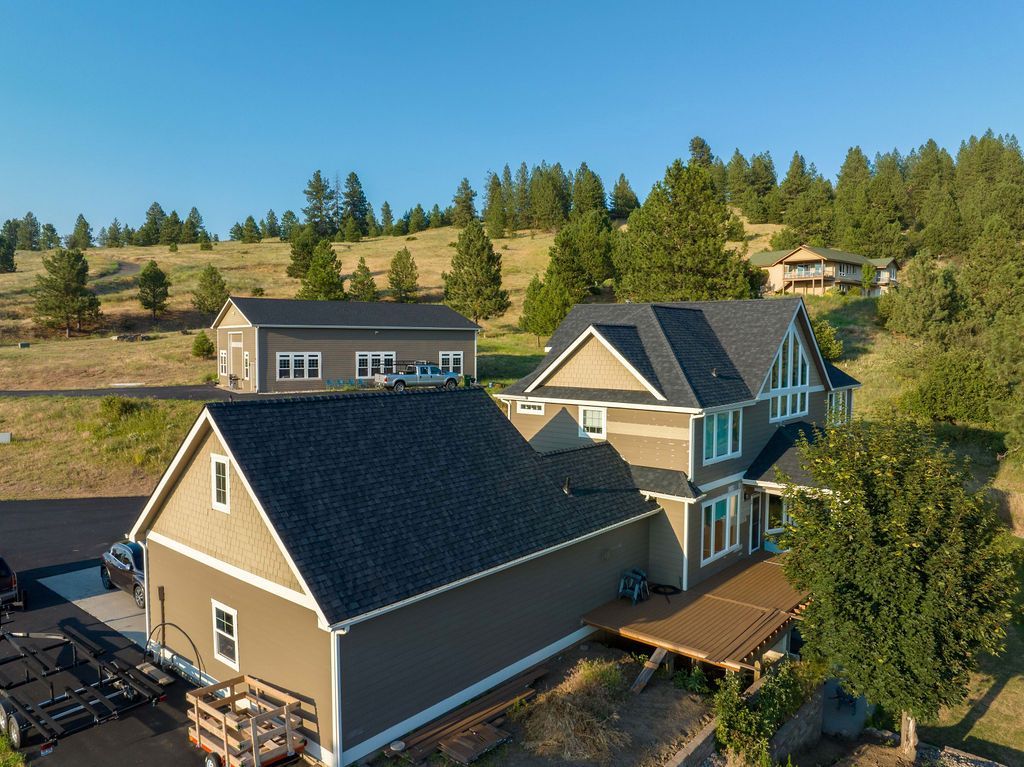 An aerial view of a house on a hill with trees in the background