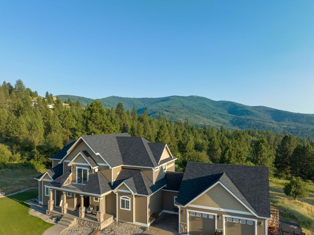 An aerial view of a large house surrounded by trees and mountains