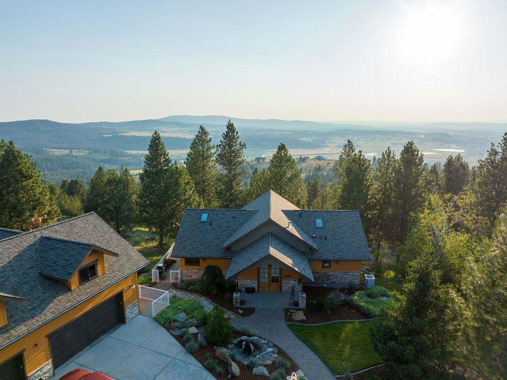 An aerial view of a house on top of a hill surrounded by trees