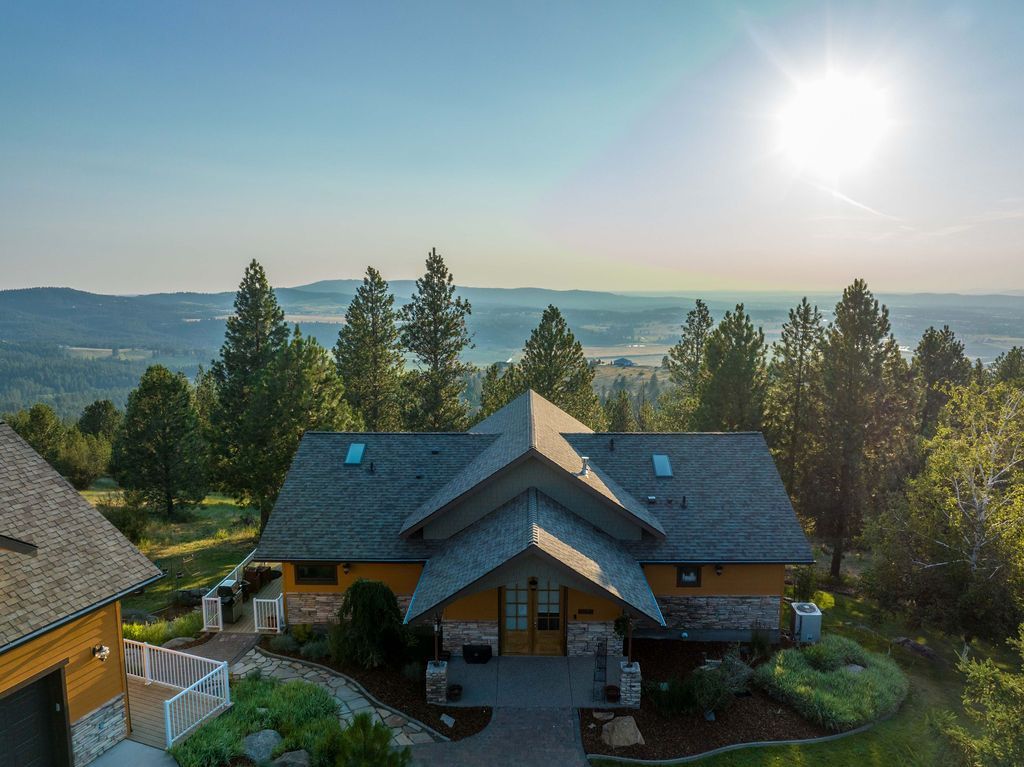 An aerial view of a house on top of a hill surrounded by trees