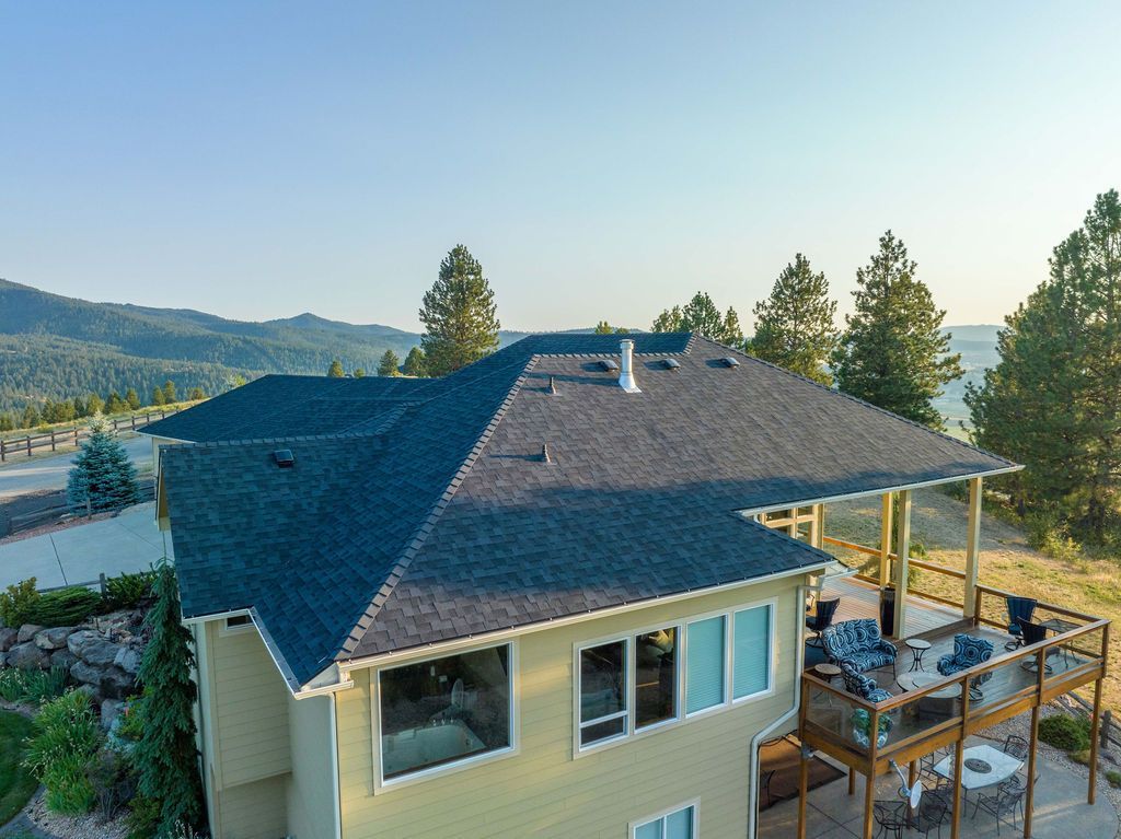 An aerial view of a large house with a blue roof and a large deck