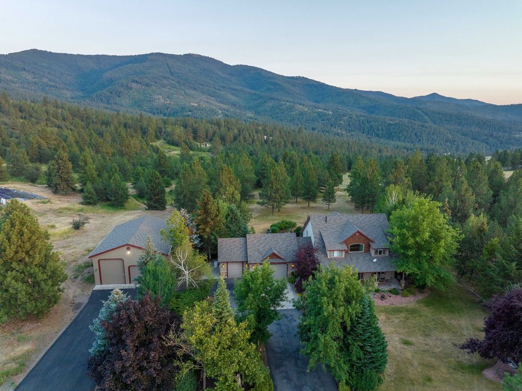 An aerial view of a large house surrounded by trees and mountains