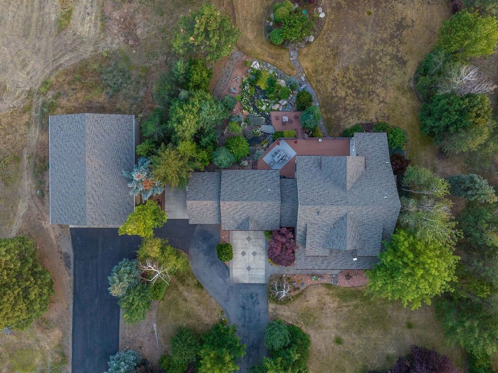 An aerial view of a house surrounded by trees and a driveway