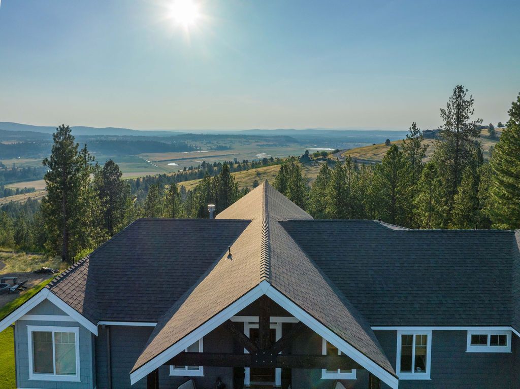 An aerial view of a house on top of a hill with trees in the background