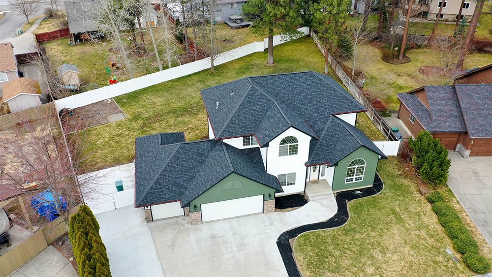 An aerial view of a house with a black roof and a large driveway