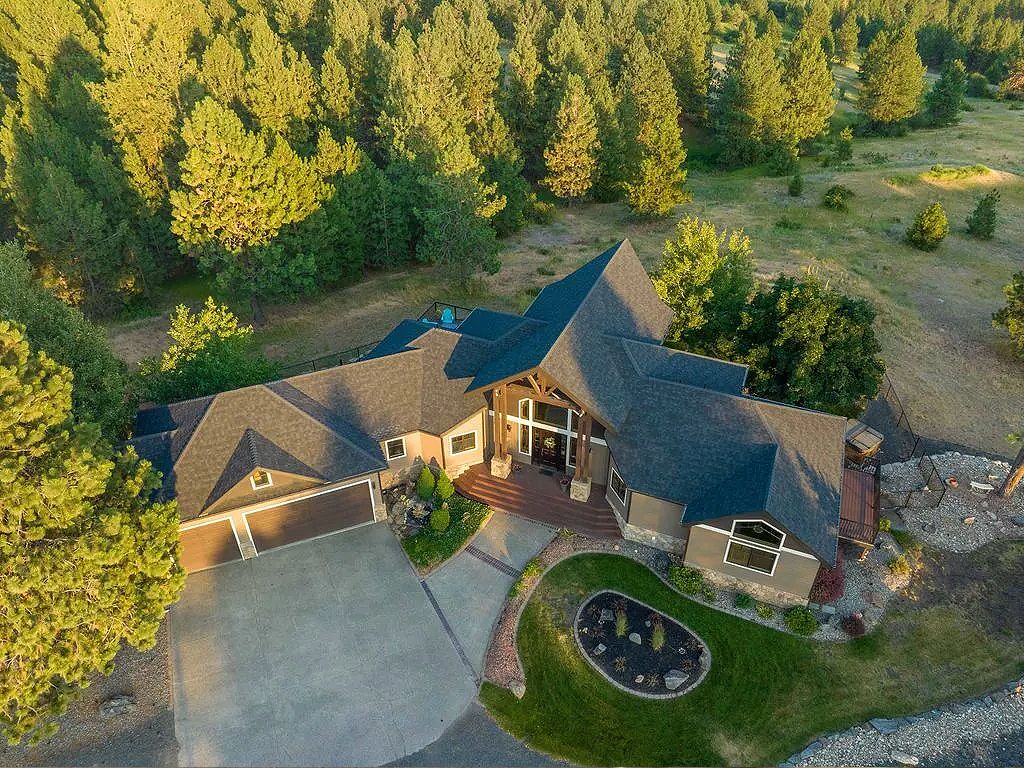 An aerial view of a large house in the middle of a forest