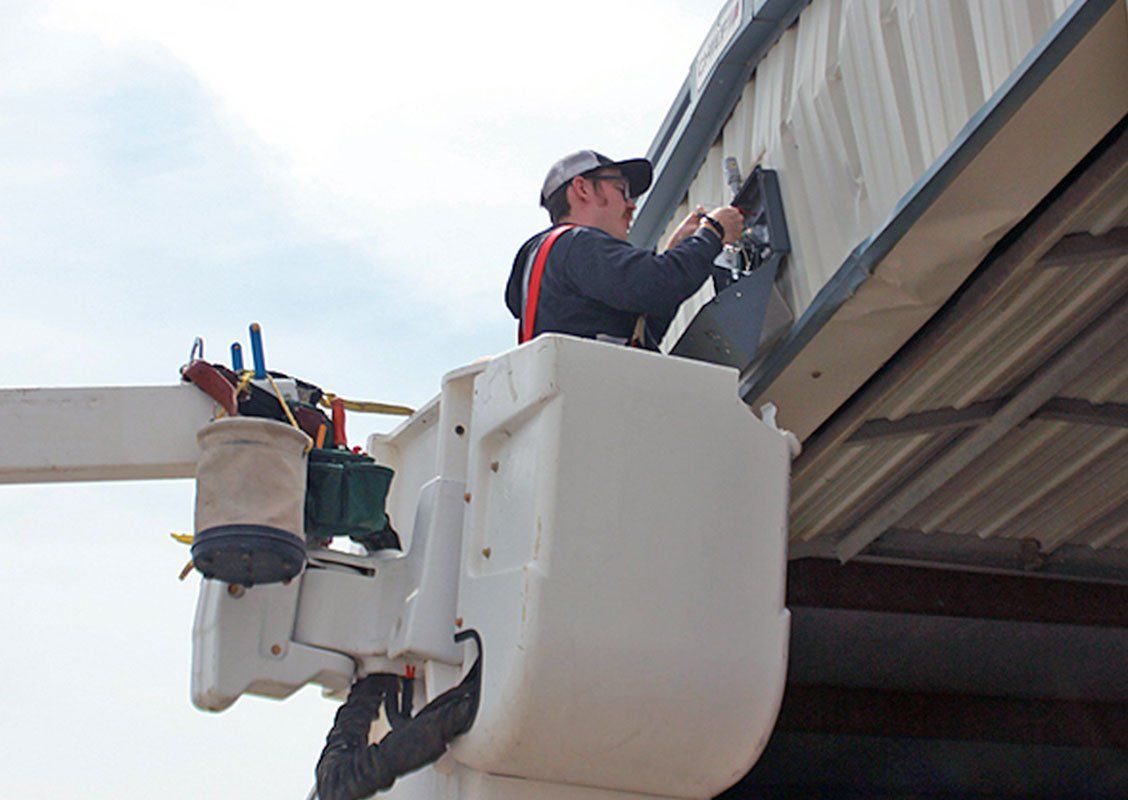 Worker repairing an electrical device on the side roof