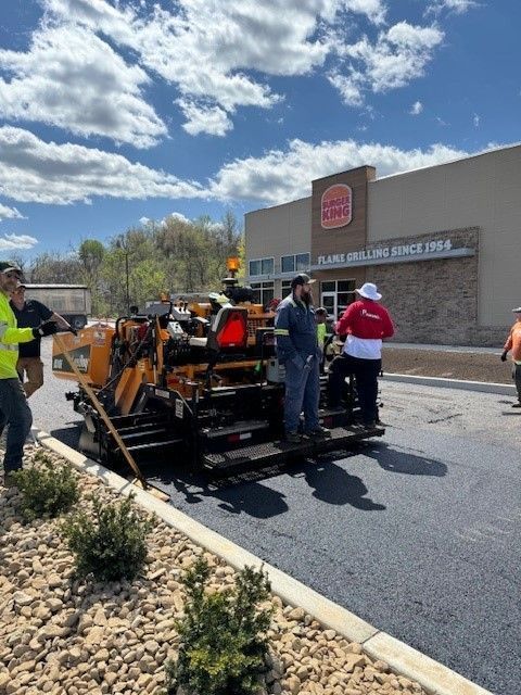 a group of people is paving the road with asphalt