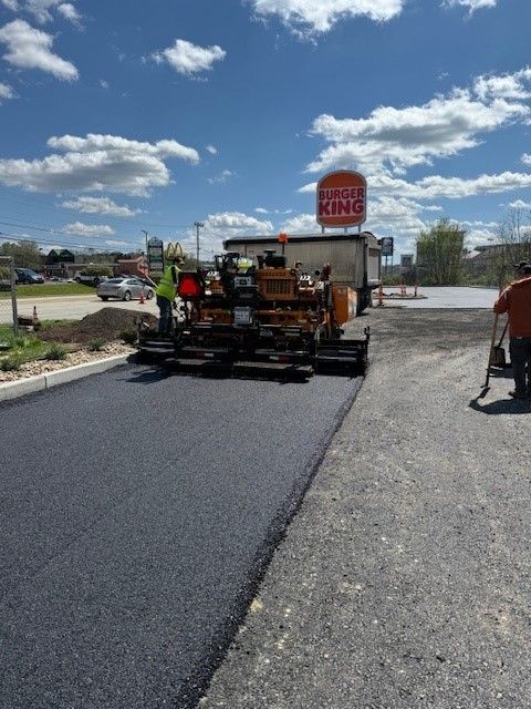 a group of men paving the road next to Burger King with asphalt