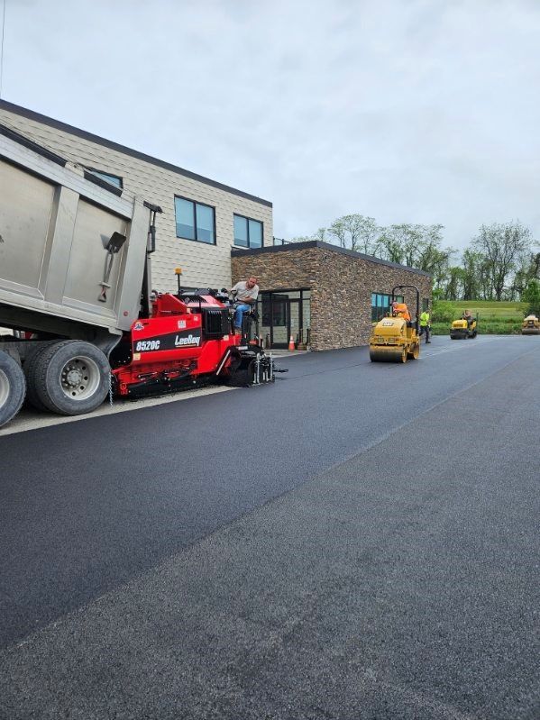 A dump truck with asphalt is parked next to a building