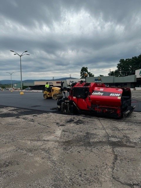 yellow and red paving equipment used to pave the parking lot with asphalt