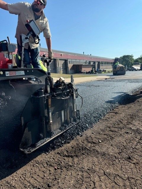 a man is standing on top of an asphalt roller