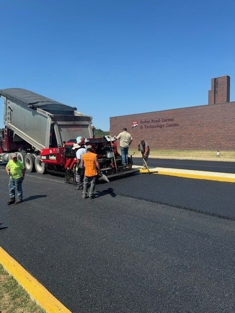 a group of men are working on a road in front of a brick building