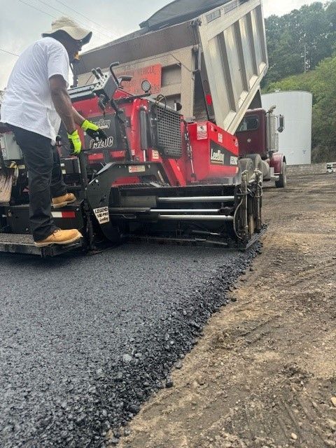 a man is riding a machine that is spreading asphalt on a road