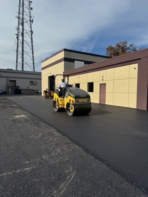 a yellow and black roller is driving down a road in front of a building