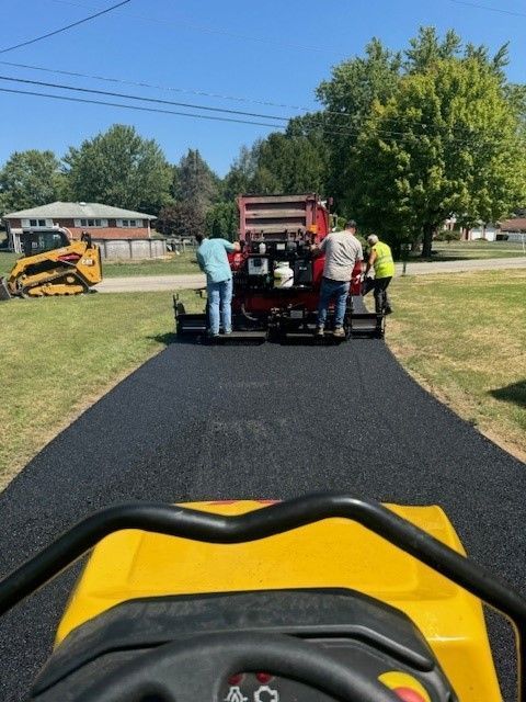 A yellow lawn mower is parked on the side of a road