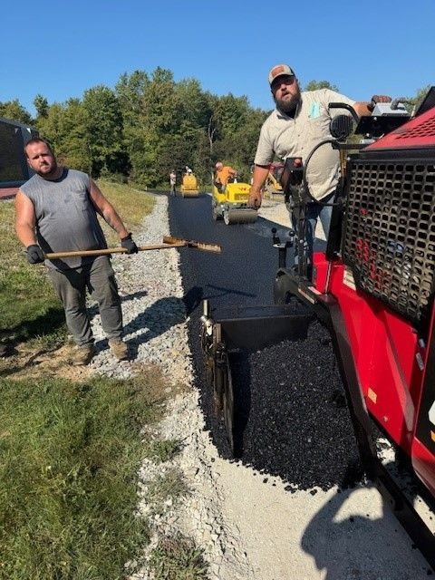 Two men are working on a road next to a red truck.