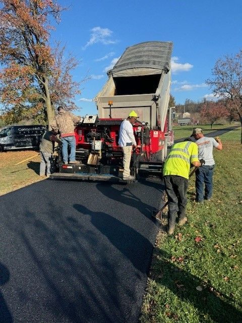 A group of men are working on a driveway next to a dump truck