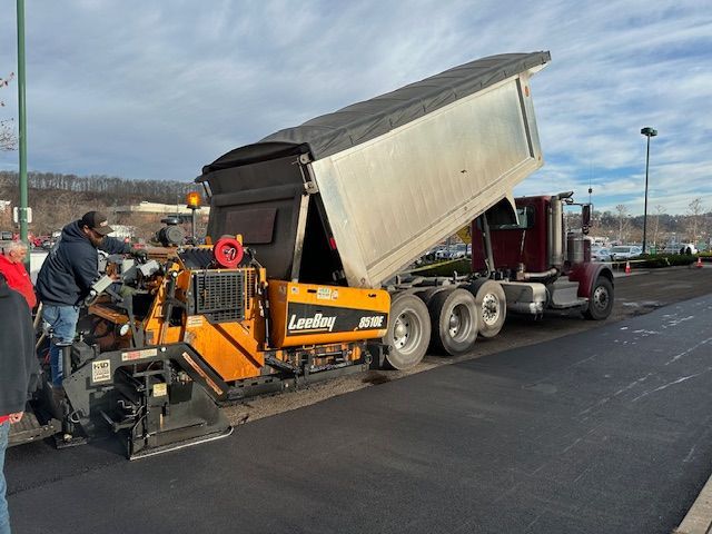 the truck is unloading asphalt