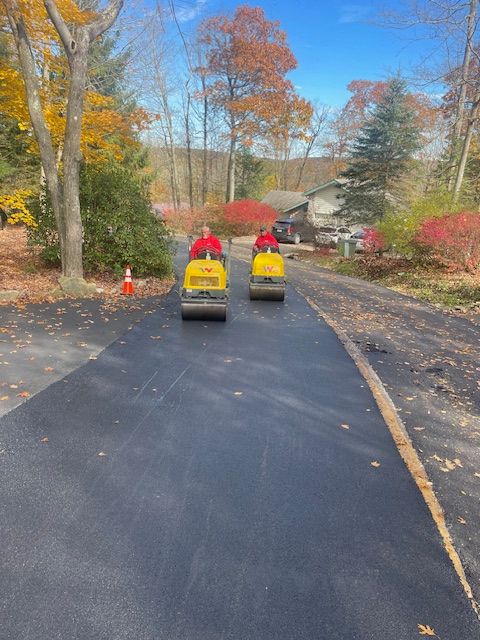 two people are riding an asphalt roller