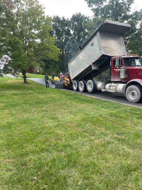 a truck unloading asphalt on the road