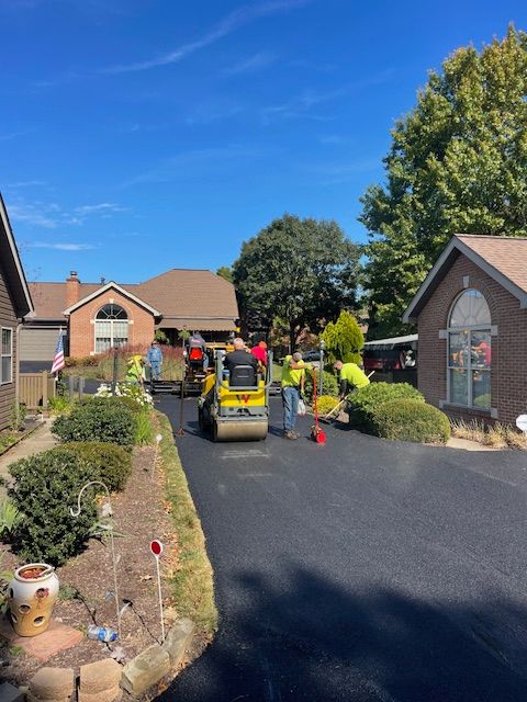 a group of people are working on a driveway in front of a house