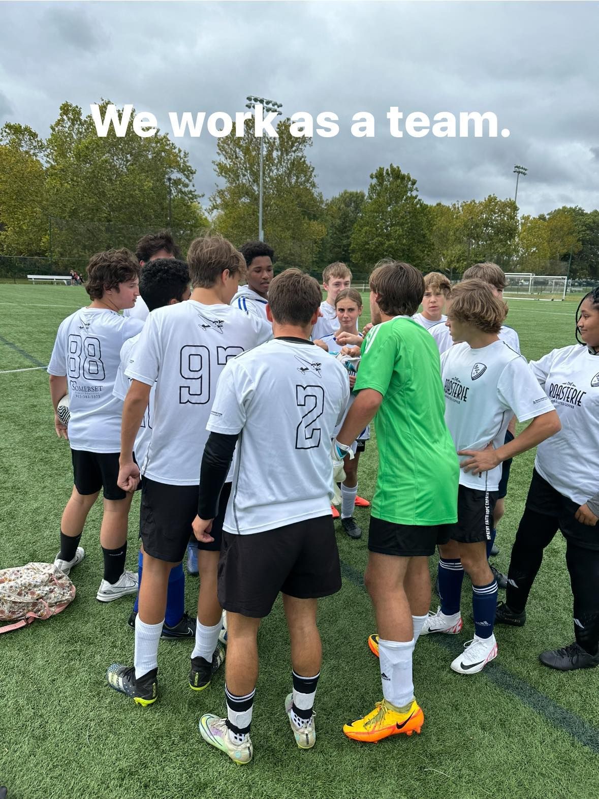 A group of young men are standing in a huddle on a soccer field.