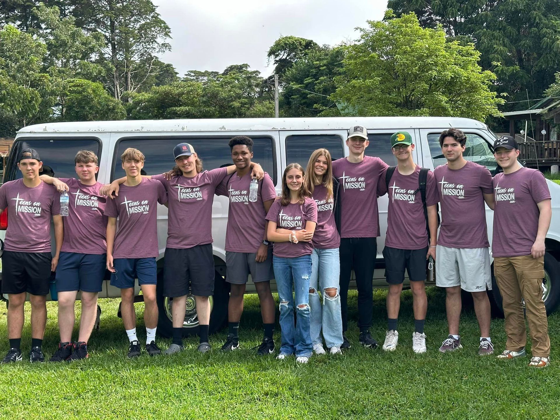 A group of young people are posing for a picture in front of a van.