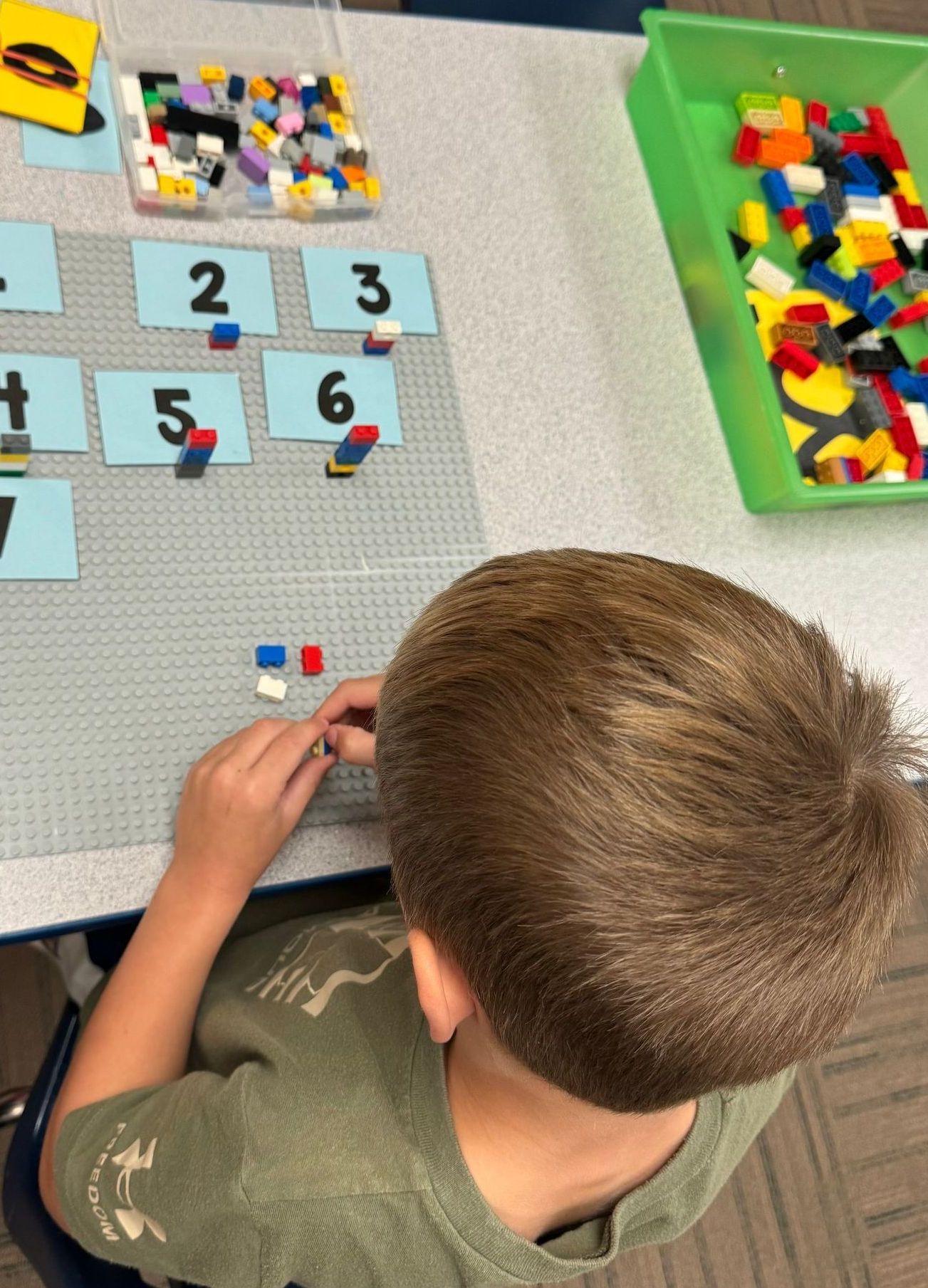 A young boy is sitting at a table playing with Lego blocks.