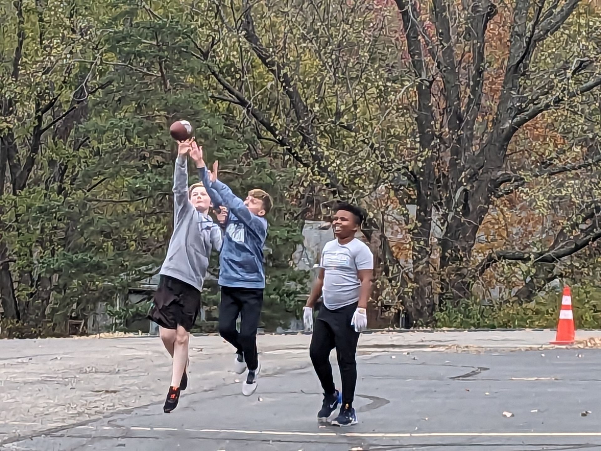 A group of young men are playing basketball in a parking lot.