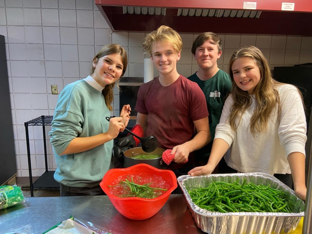 A group of young people are preparing food in a kitchen.