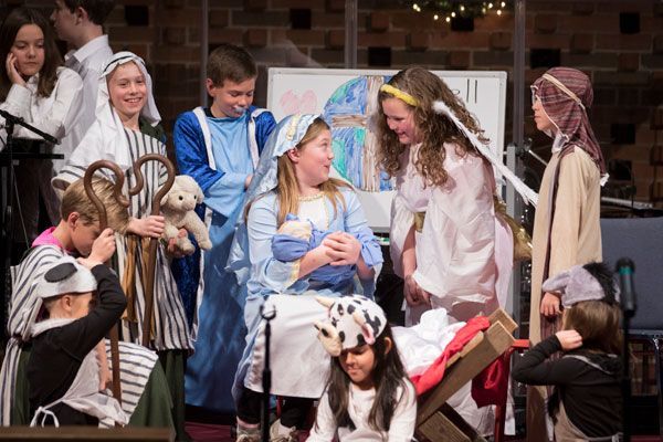 A group of children dressed in nativity costumes are performing a nativity scene.