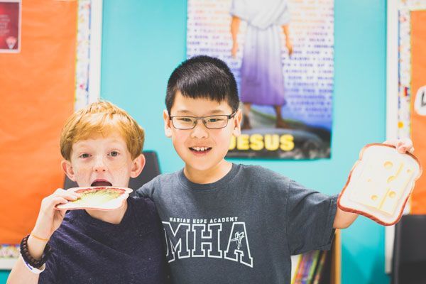 Two young boys holding toy sandwiches.