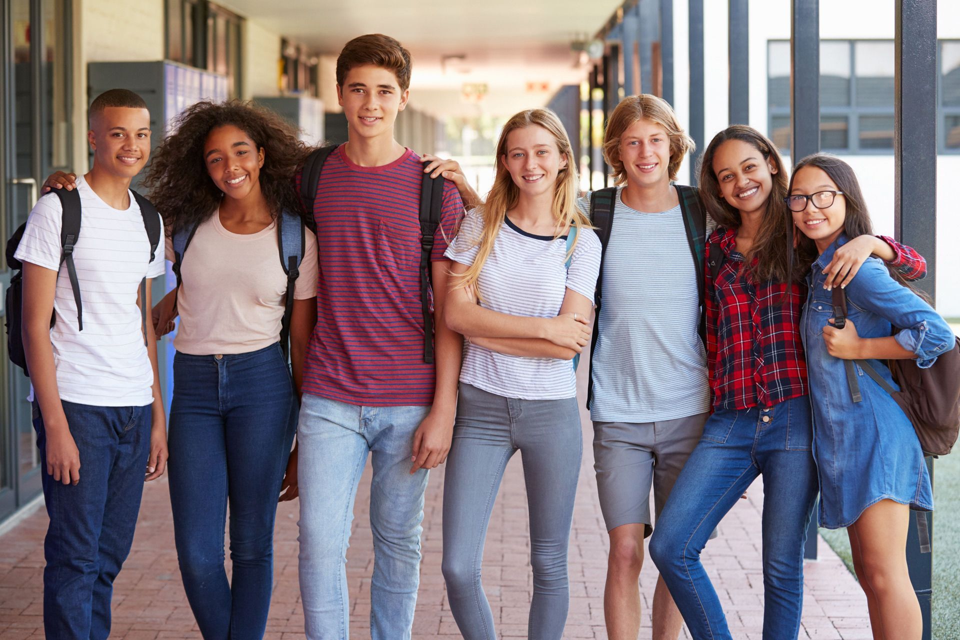 A group of young people are posing for a picture in a hallway.