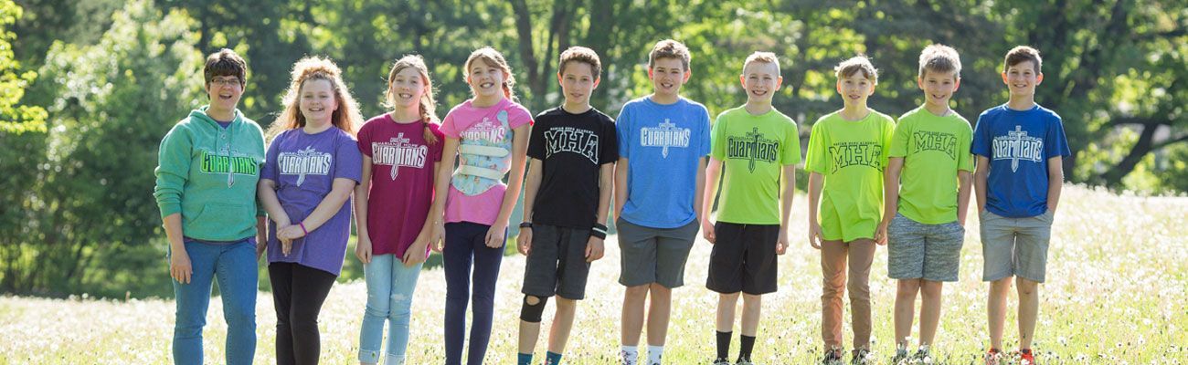 A group of children are posing for a picture in a field.