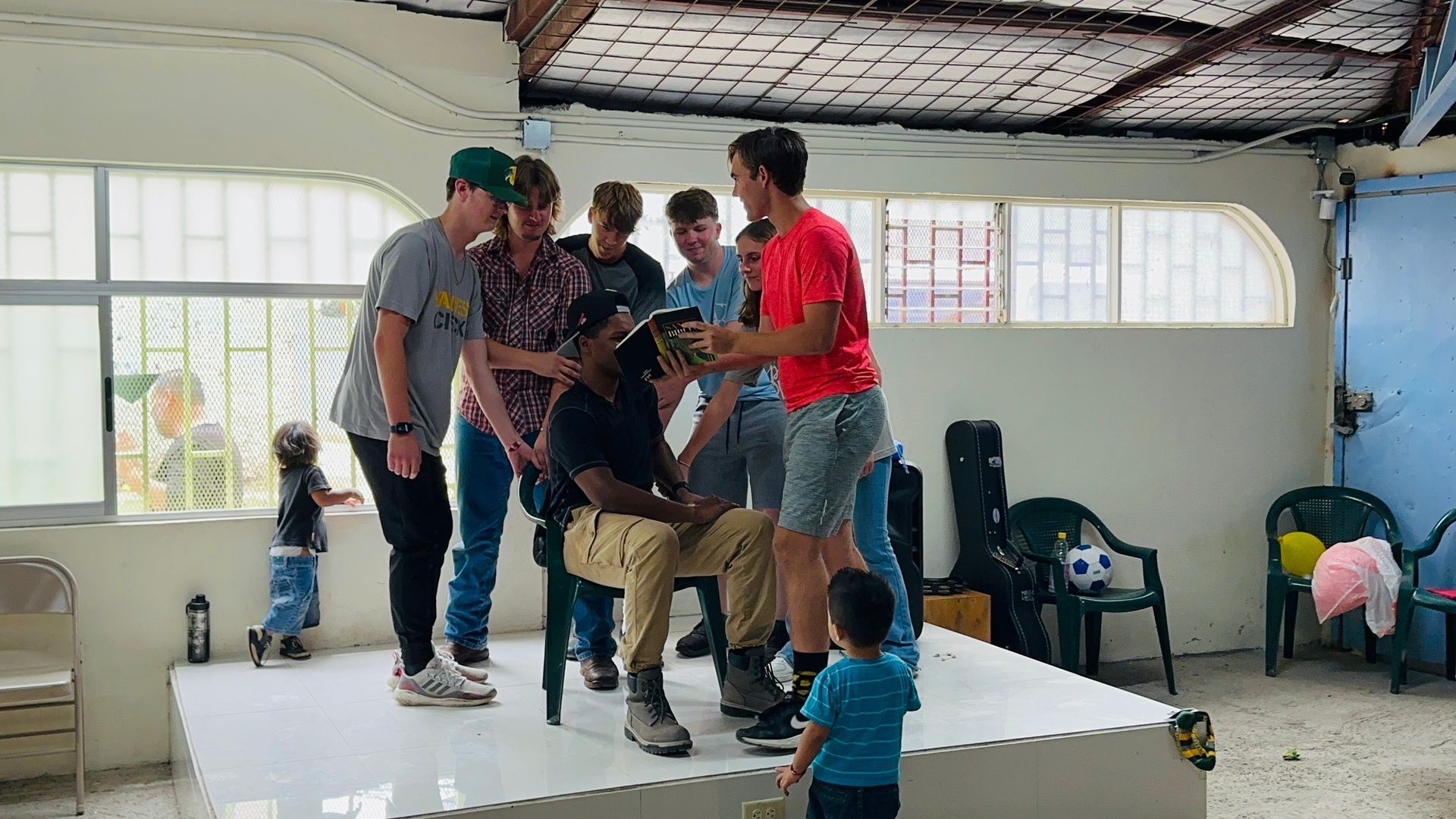 A group of people are standing around a stage in a room.