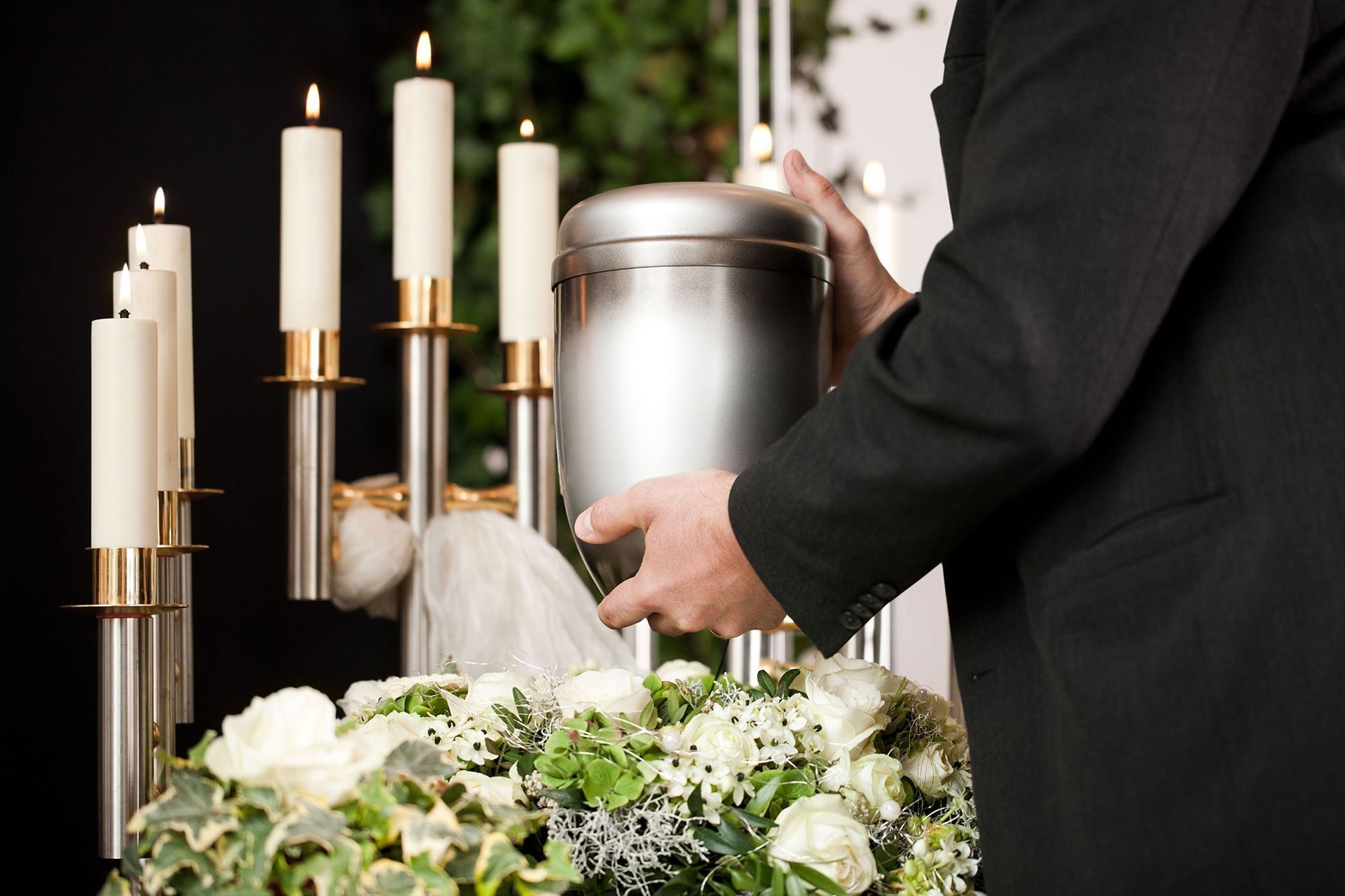 A man is putting a candle in a urn at a funeral.