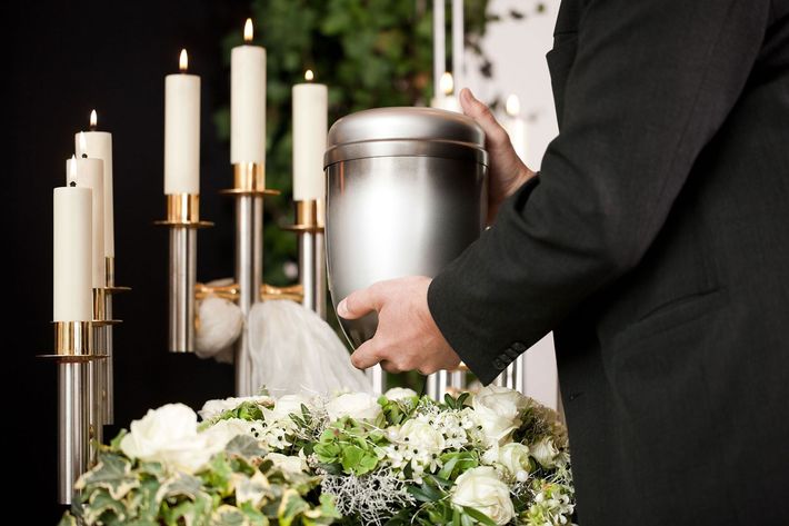 A man is putting a candle in a urn at a funeral.