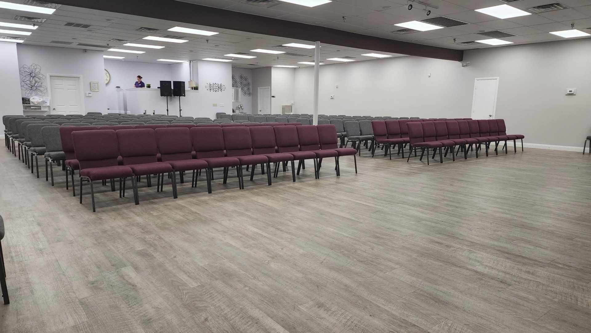A large empty room with rows of chairs and a wooden floor.