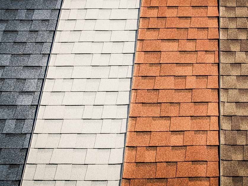 Close-up of multicolored roof shingles in gray, white, and orange sections