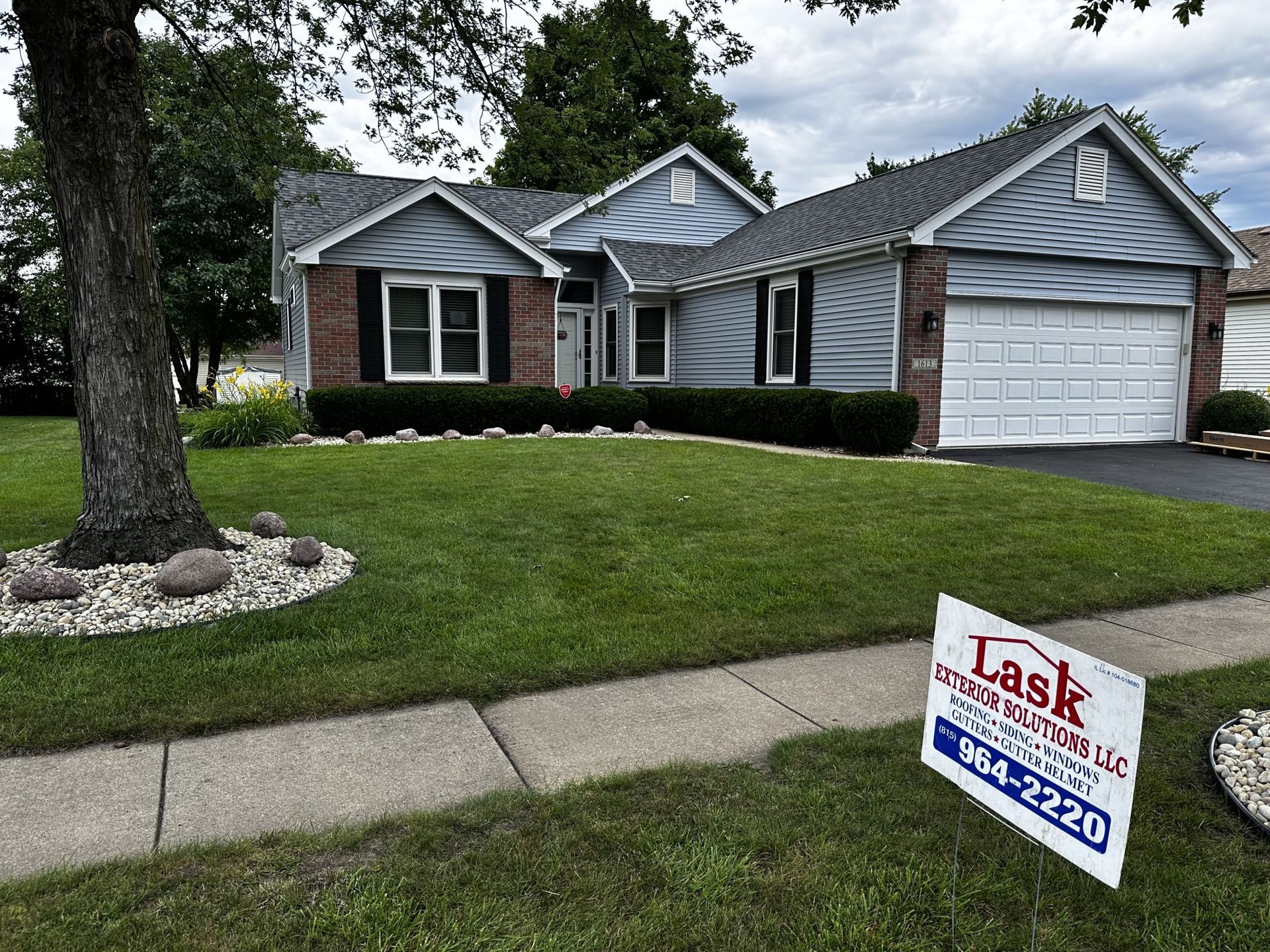 Suburban house with a green lawn and a real estate sign in the front yard.